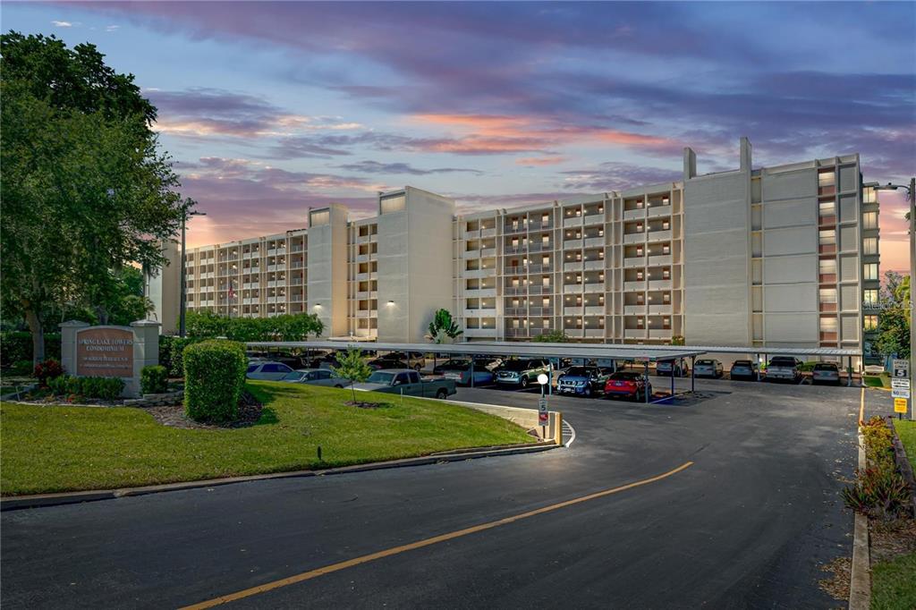 An exterior view of a multi-story apartment building with a covered parking lot in front — 700 MIRROR TERRACE NW UNIT 506, WINTER HAVEN, FL