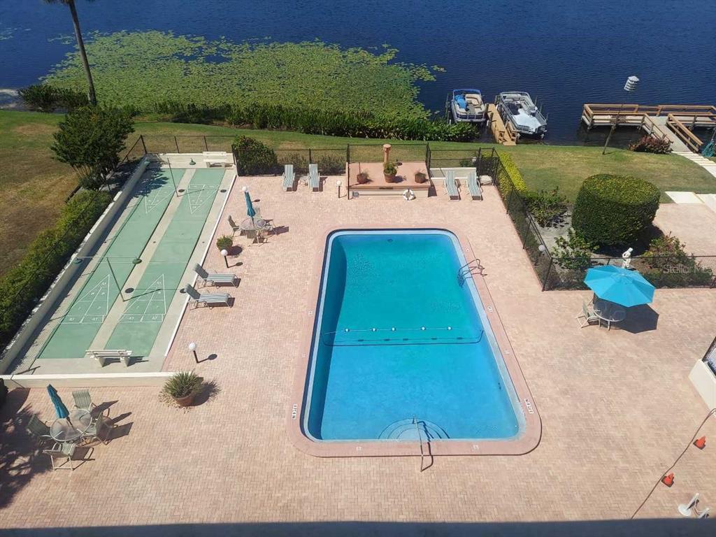 An aerial view of a swimming pool, shuffleboard court, and boat dock by a lake — 700 MIRROR TERRACE NW UNIT 506, WINTER HAVEN, FL