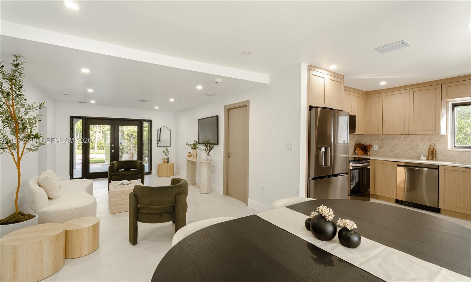An open-concept living room and kitchen feature light wood cabinetry, stainless steel appliances, and modern furniture — 1221 Biarritz Dr, Miami Beach FL 33141, MIAMI BEACH, FL