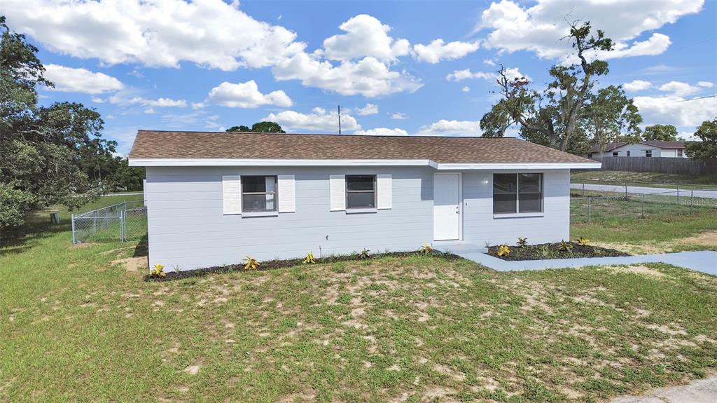A single-story house with light gray siding, white shutters, and a brown shingled roof — 9667 BAYSIDE COURT, SPRING HILL, FL