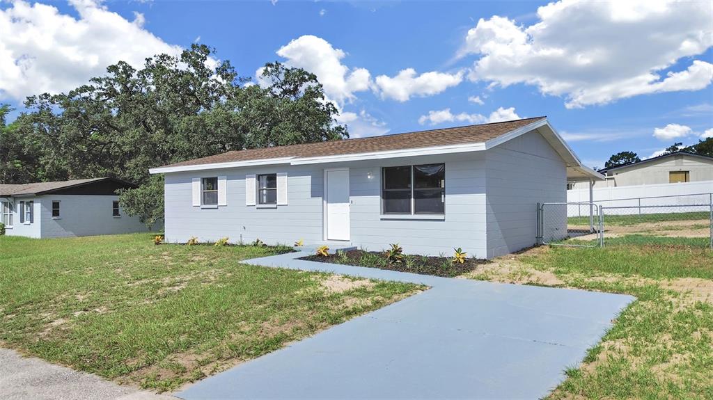 A light blue, single-story house with a concrete walkway and a chain-link fence — 9667 BAYSIDE COURT, SPRING HILL, FL