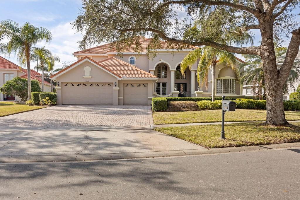 A two-story suburban house with a tile roof, three-car garage, and a paved driveway — 9050 DANCY TREE COURT, ORLANDO, FL