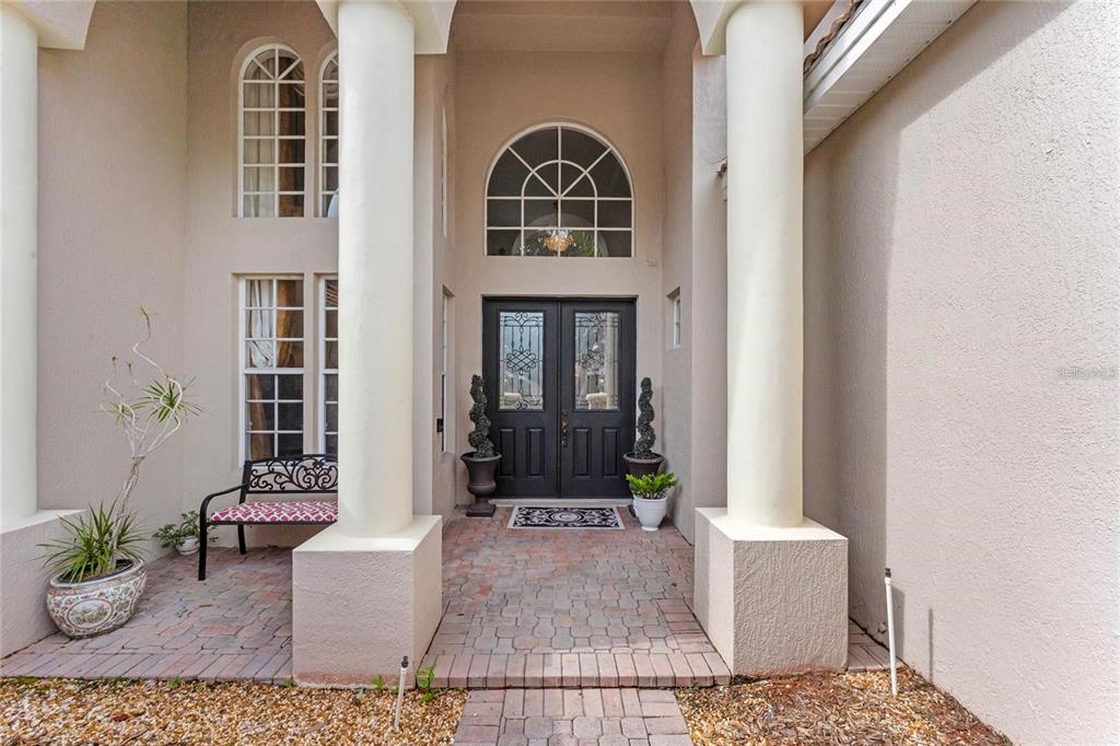 A front entryway features a brick porch, two large columns, and double doors with glass — 9050 DANCY TREE COURT, ORLANDO, FL