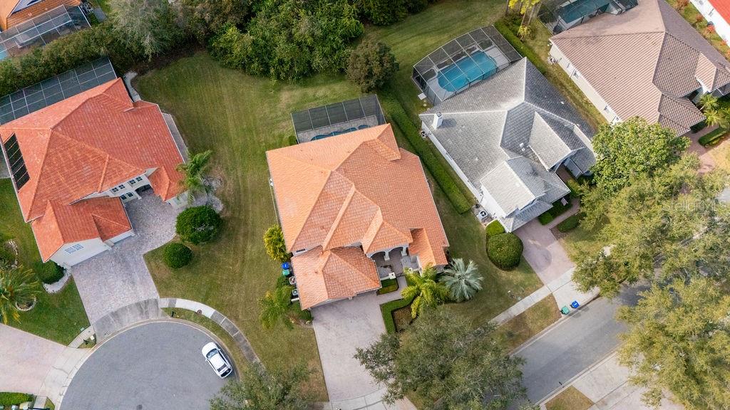 An aerial view shows three suburban houses with tiled roofs, swimming pools, and driveways — 9050 DANCY TREE COURT, ORLANDO, FL