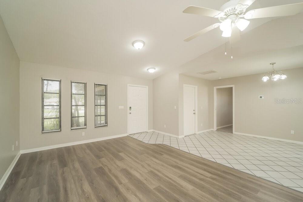 An open-concept living and dining area features wood-look flooring, tile entry, and a ceiling fan — 1329 SE 12TH STREET, CAPE CORAL, FL