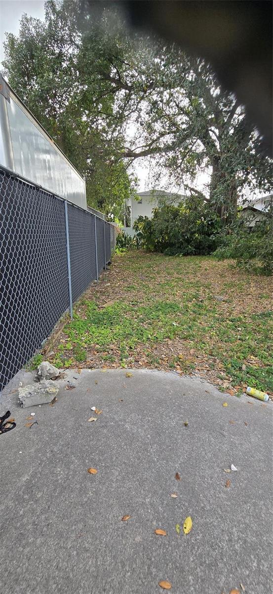 A concrete patio area leads to a grassy backyard enclosed by a chain-link fence — 2948 NW 46th Street, Miami FL 33142, MIAMI, FL