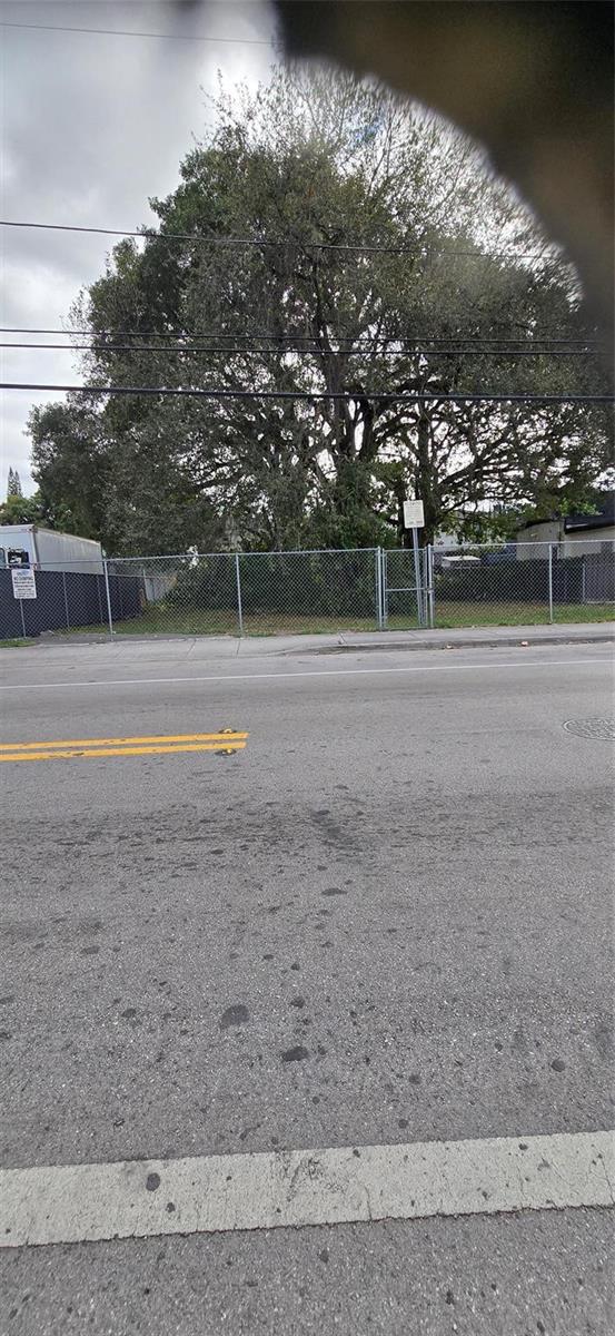 A fenced, vacant lot with a large tree sits behind a paved road — 2948 NW 46th Street, Miami FL 33142, MIAMI, FL
