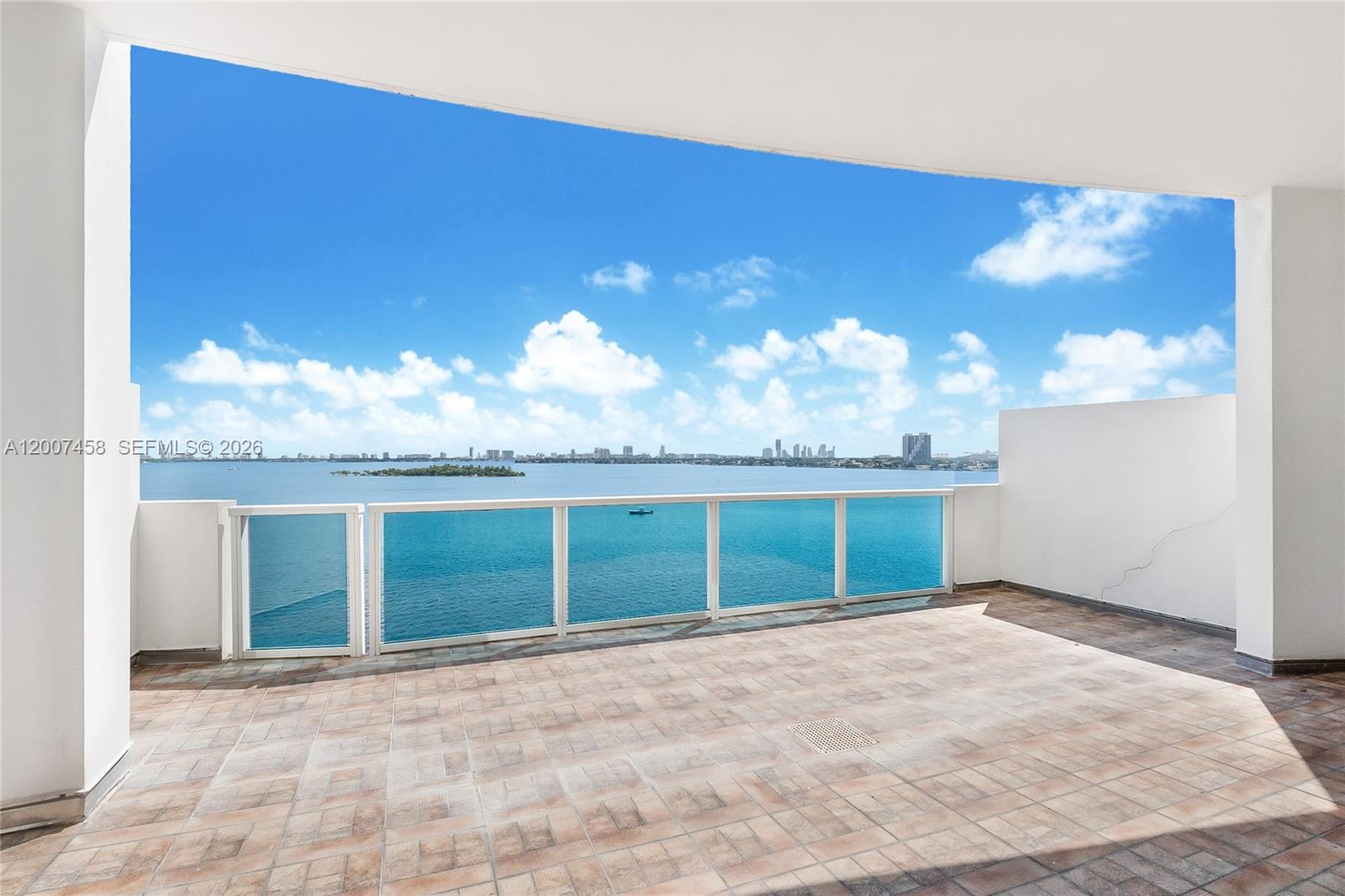 A spacious balcony features tiled flooring, a glass railing, and an expansive ocean view — 725 NE 22nd St # 7B, Miami FL 33137, MIAMI, FL