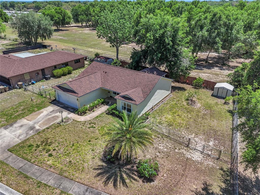 An aerial view shows a single-story house with a brown roof, garage, and fenced yard — 3624 TROUT AVENUE, FRUITLAND PARK, FL