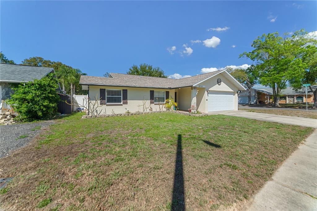 A single-story house with a beige exterior, a two-car garage, and a front lawn — 8715 HUNTSMAN LANE, PORT RICHEY, FL
