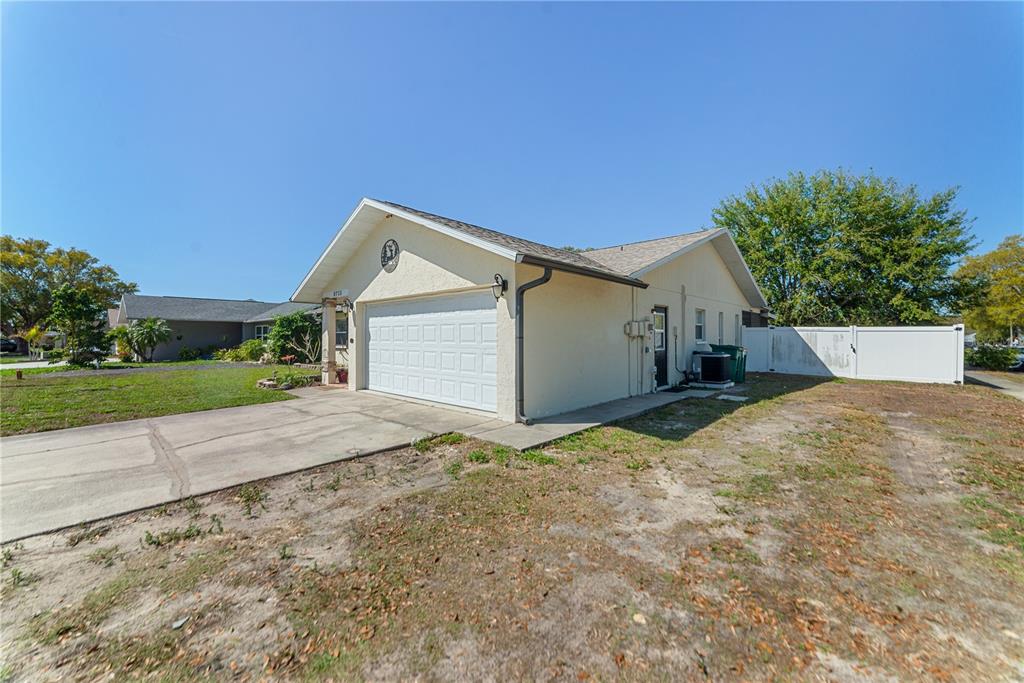 A single-story house with a white garage door, stucco exterior, and a concrete driveway — 8715 HUNTSMAN LANE, PORT RICHEY, FL
