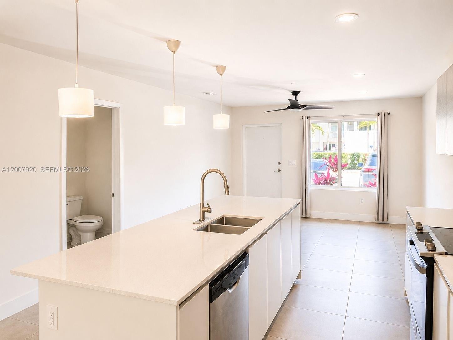 A modern kitchen features a white quartz island, stainless steel appliances, and tile flooring — 2505 NE 193rd St # 4112, Miami FL 33180, MIAMI, FL