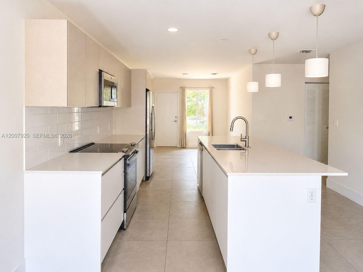A modern kitchen features white cabinets, quartz countertops, a center island, and stainless steel appliances — 2505 NE 193rd St # 4112, Miami FL 33180, MIAMI, FL