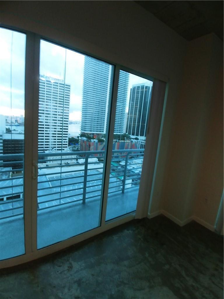 An interior view of a room with floor-to-ceiling windows overlooking a city skyline — 133 NE 2nd Avenue # 1812, Miami FL 33132, MIAMI, FL