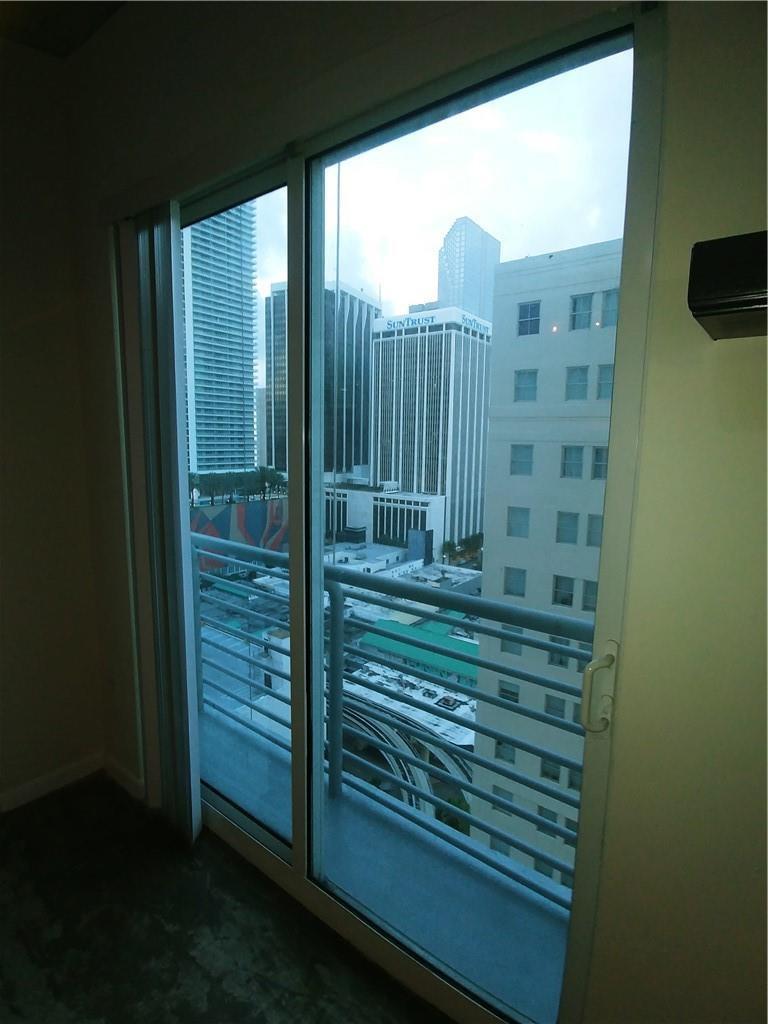 A view of city skyscrapers and a balcony through a sliding glass door — 133 NE 2nd Avenue # 1812, Miami FL 33132, MIAMI, FL