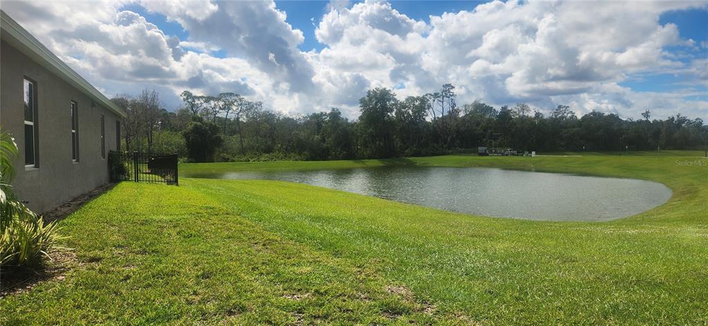 A side view of a house exterior overlooking a grassy lawn and a retention pond — 9032 CAPE COD ROAD, DELAND, FL