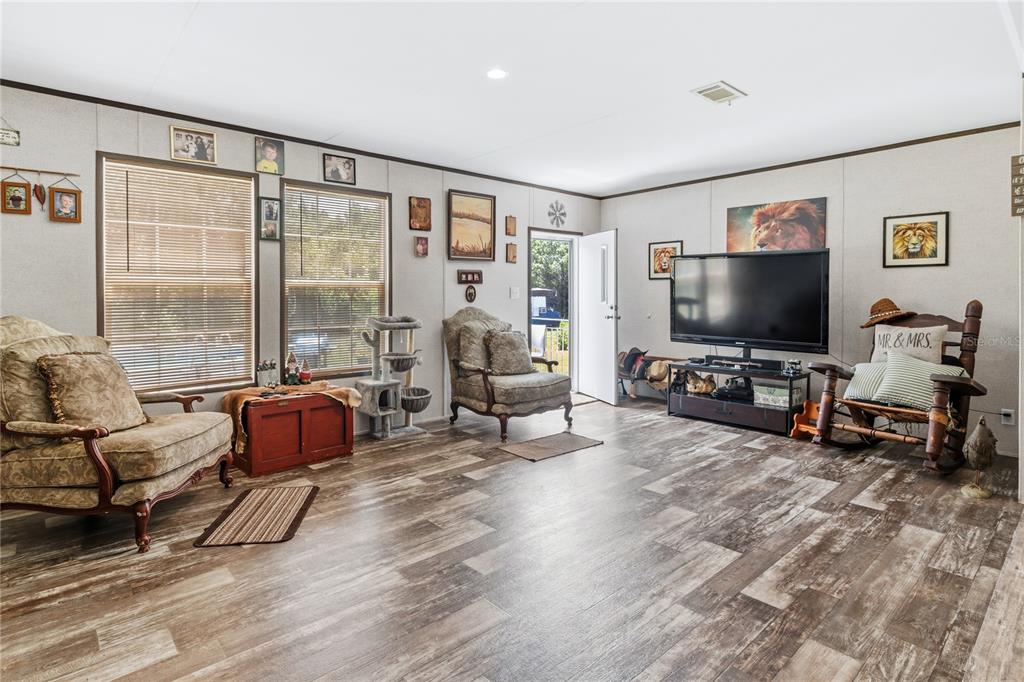 A living room features wood-look flooring, two armchairs, a rocking chair, and a television stand — 1833 E SUNNYSIDE DRIVE, LORIDA, FL