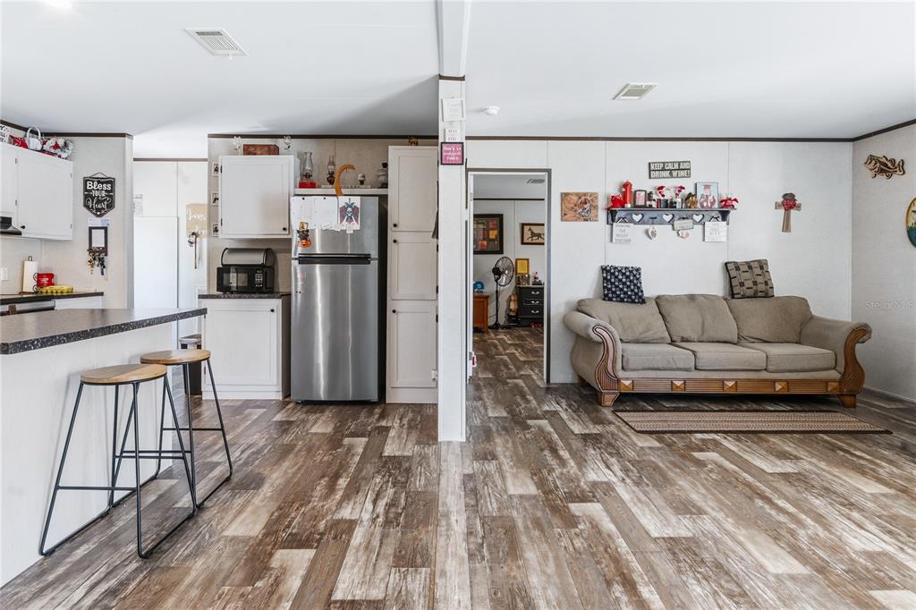 A kitchen with a breakfast bar and stainless steel refrigerator opens into a living area — 1833 E SUNNYSIDE DRIVE, LORIDA, FL
