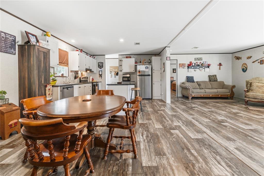 An open-concept kitchen and living area features wood-look flooring, a wooden dining set, and cabinetry — 1833 E SUNNYSIDE DRIVE, LORIDA, FL