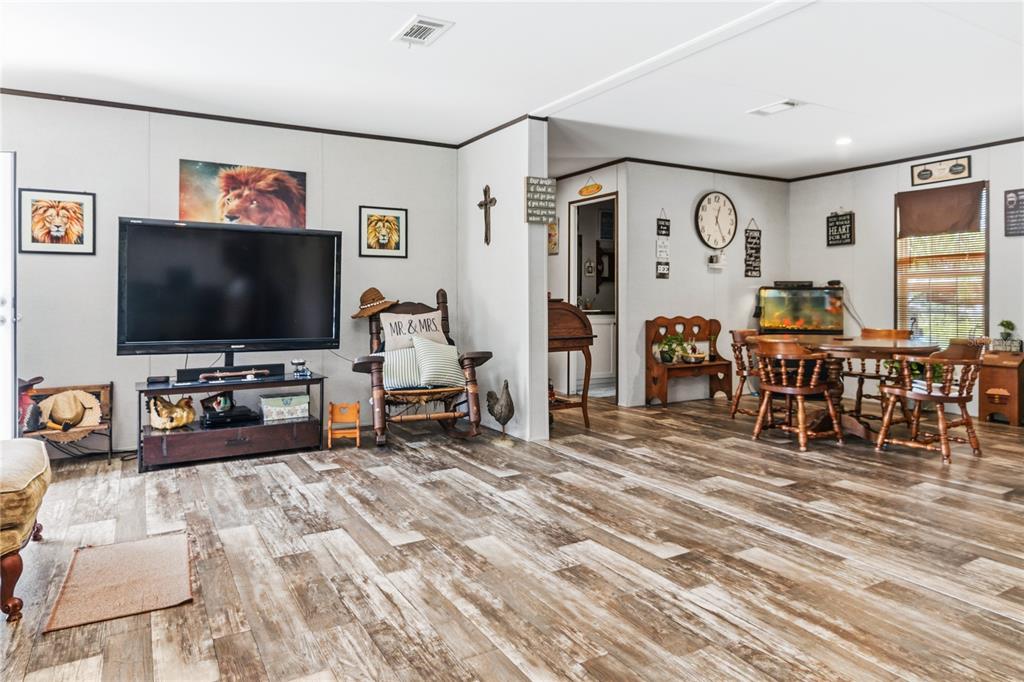 A living and dining area with wood-look flooring, a television, and rustic wooden furniture — 1833 E SUNNYSIDE DRIVE, LORIDA, FL