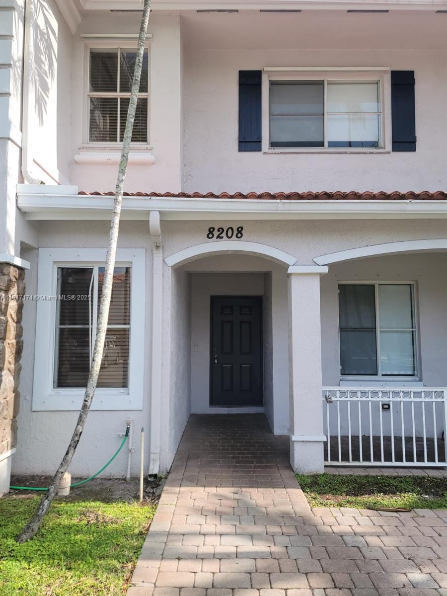 The exterior of a two-story townhouse features a paved walkway leading to a dark front door — 8208 SW 25th Ct # 103, Miramar FL 33025, MIRAMAR, FL