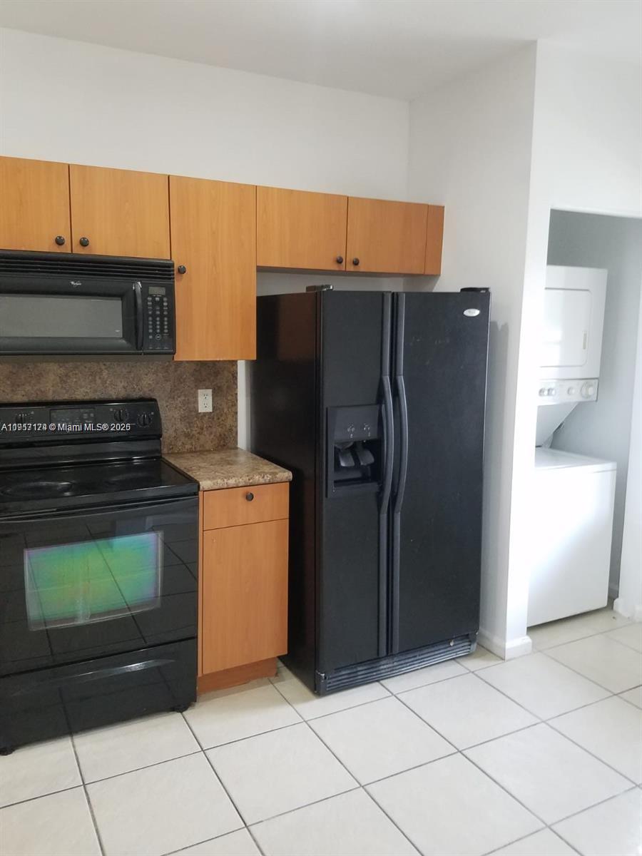 A kitchen features black appliances, light wood cabinets, and white tile flooring — 8208 SW 25th Ct # 103, Miramar FL 33025, MIRAMAR, FL