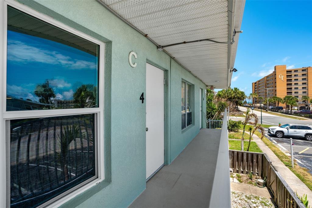 An exterior walkway leads to a white door labeled number four on a teal building — 420 TYLER AVENUE UNIT 4-3, CAPE CANAVERAL, FL