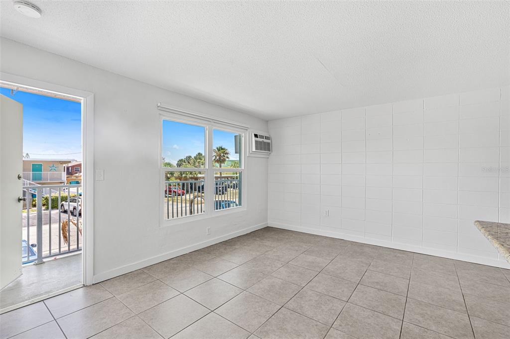 An empty room with tiled floors, a white block wall, and an open balcony door — 420 TYLER AVENUE UNIT 4-3, CAPE CANAVERAL, FL