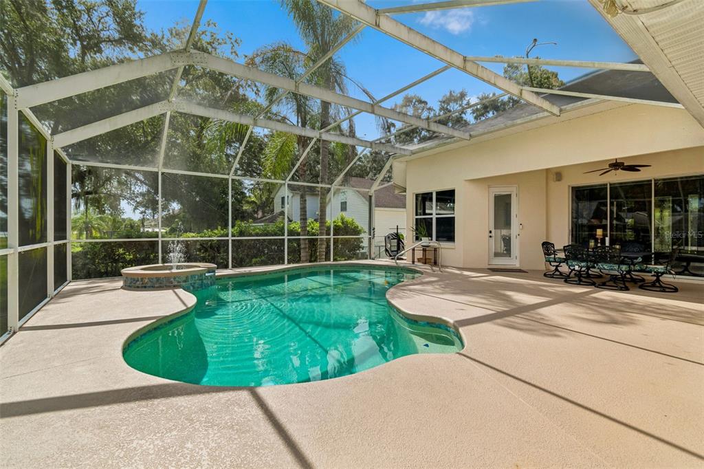 A screened-in patio features a swimming pool with an attached spa and outdoor dining area — 1514 BOOTH DRIVE, VALRICO, FL
