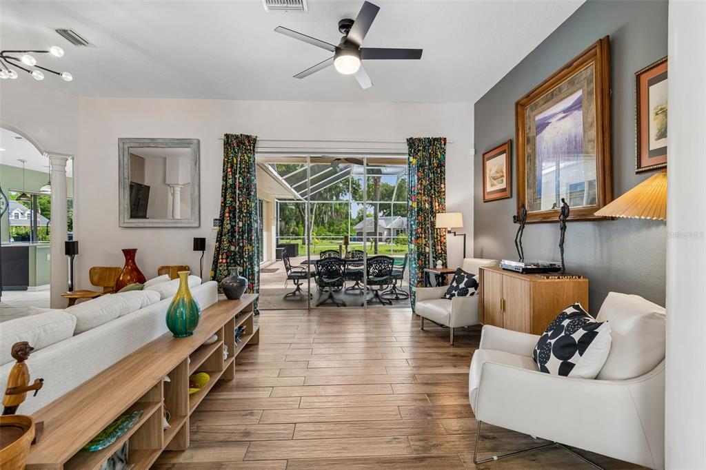 A living room with wood-look tile floors, a ceiling fan, and sliding glass doors to a patio — 1514 BOOTH DRIVE, VALRICO, FL