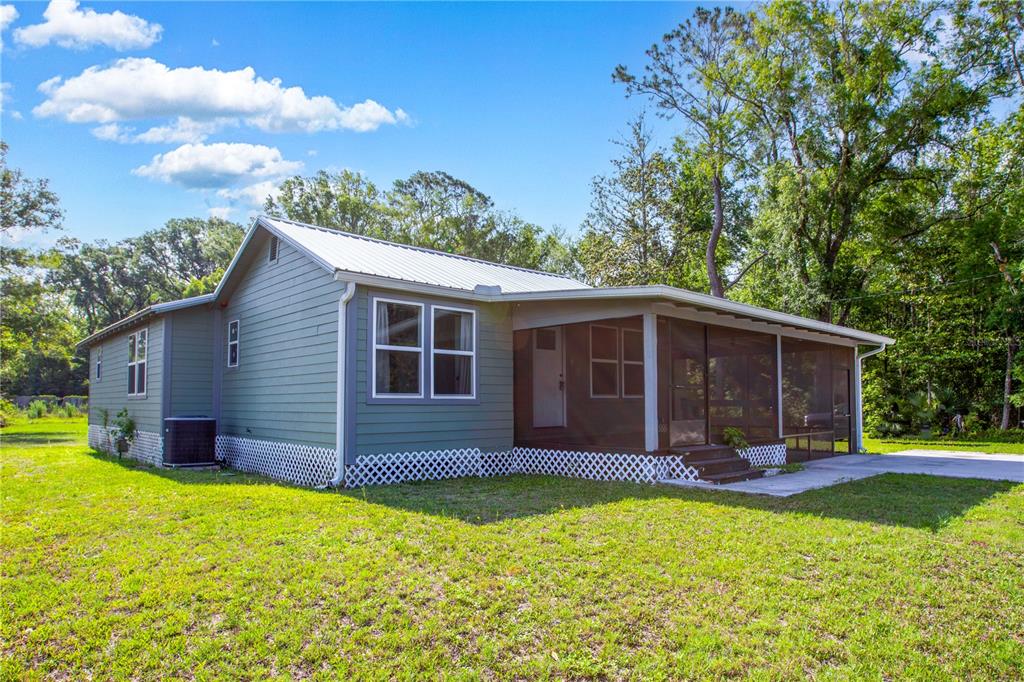 A single-story house with green siding, a metal roof, and a screened-in porch — 408 S ORANGE STREET, STARKE, FL