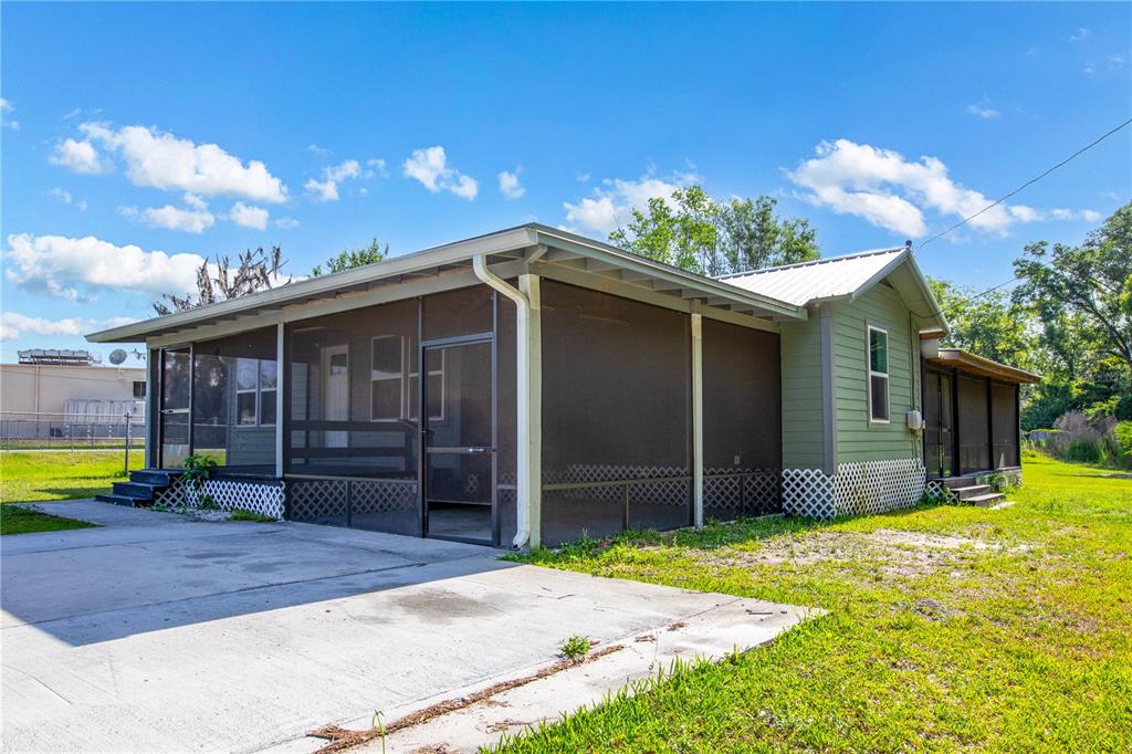A single-story house with green siding and a large screened-in porch — 408 S ORANGE STREET, STARKE, FL