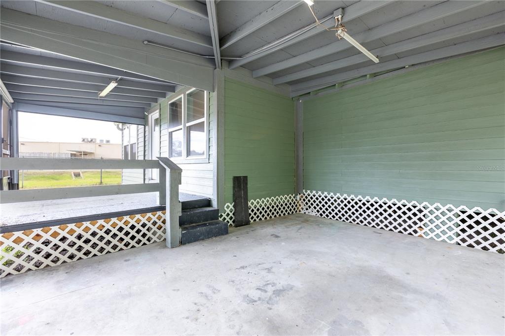 A covered concrete patio features green siding, white lattice skirting, and a small wooden staircase — 408 S ORANGE STREET, STARKE, FL