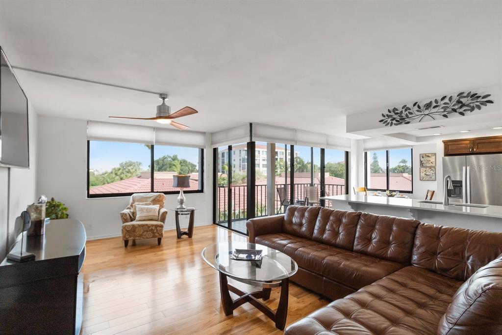 A living room with a brown leather sectional, glass coffee table, and balcony access — 6269 PALMA DEL MAR BOULEVARD S UNIT 302, ST PETERSBURG, FL