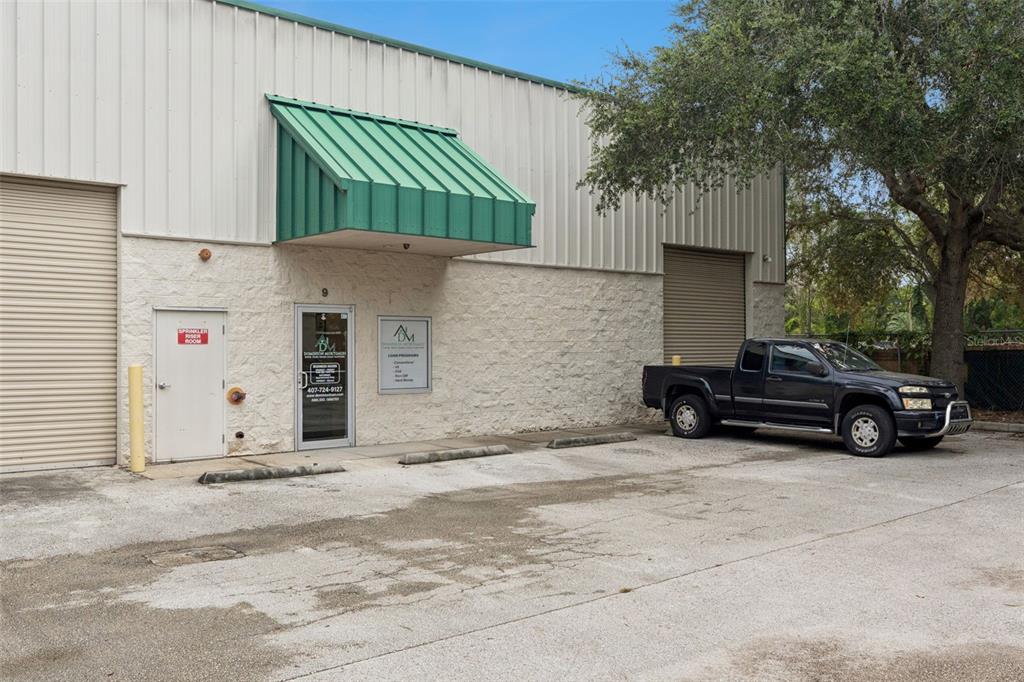 An exterior view of a commercial warehouse building with a green awning and a parked truck — 3239 OLD WINTER GARDEN ROAD UNIT 9A & 9B, ORLANDO, FL