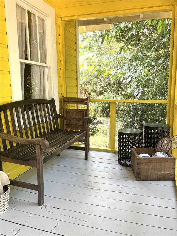 A wooden bench sits on a yellow-walled porch with a gray floor and metal tables — 17847 COUNTY ROAD 455, CLERMONT, FL