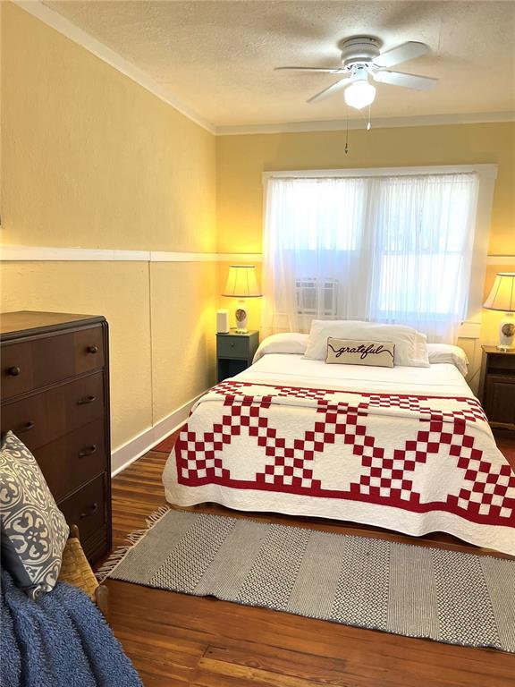 A bedroom features a bed with a red and white quilt, hardwood floors, and furniture — 17847 COUNTY ROAD 455, CLERMONT, FL