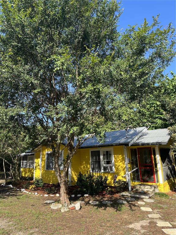 A yellow cottage with a metal roof is partially shaded by a large tree — 17847 COUNTY ROAD 455, CLERMONT, FL