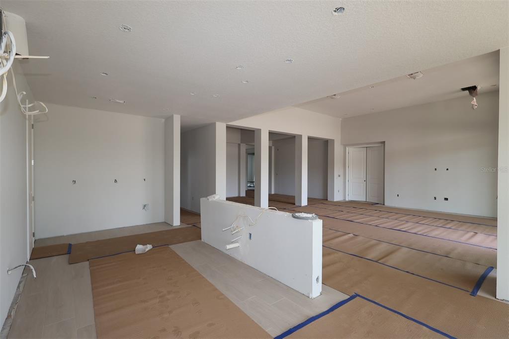 An unfinished open-concept room features white walls, recessed lighting, and protective paper on the floor — 17036 OVERSTORY ROAD, ORLANDO, FL