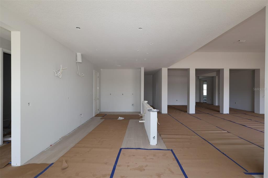 An unfinished interior space features white walls, recessed lighting, and floors covered in protective paper — 17036 OVERSTORY ROAD, ORLANDO, FL