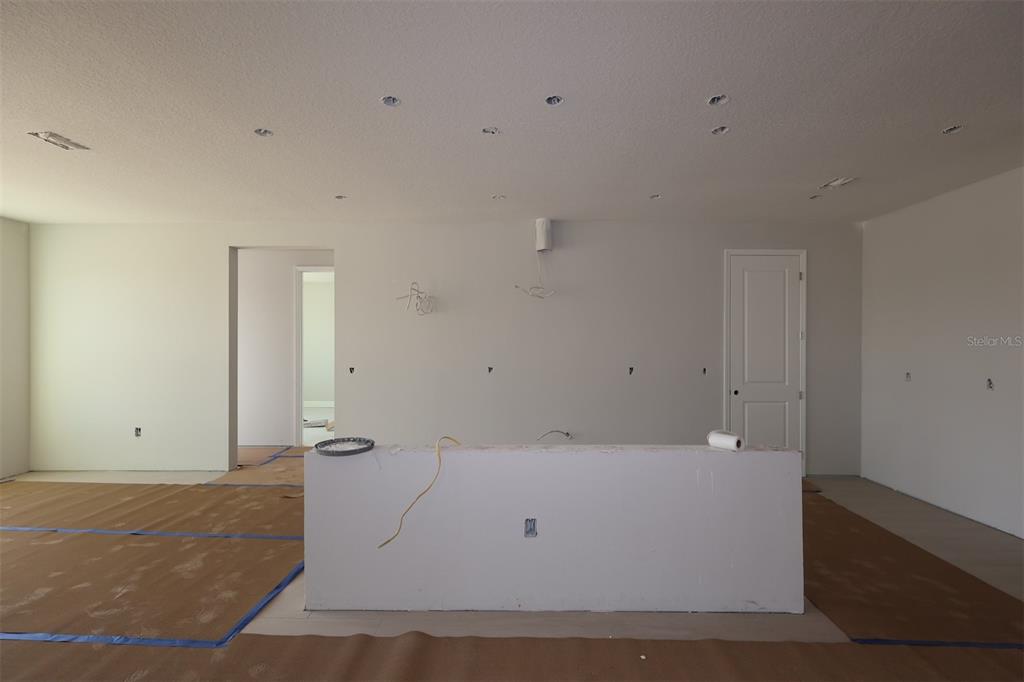 An unfinished room features a central kitchen island, recessed lighting, and protective floor paper — 17036 OVERSTORY ROAD, ORLANDO, FL