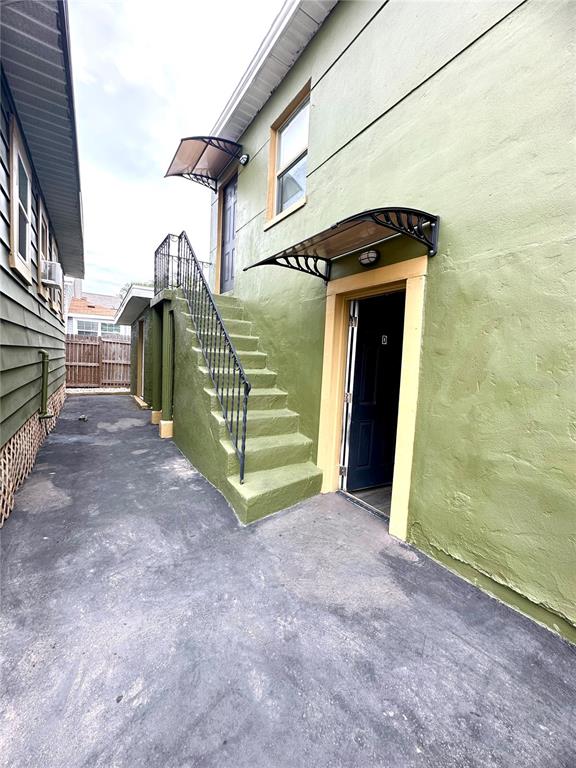 An exterior view of a green building featuring an outdoor staircase and two entry doors — 2907 N 15TH STREET UNIT D, TAMPA, FL