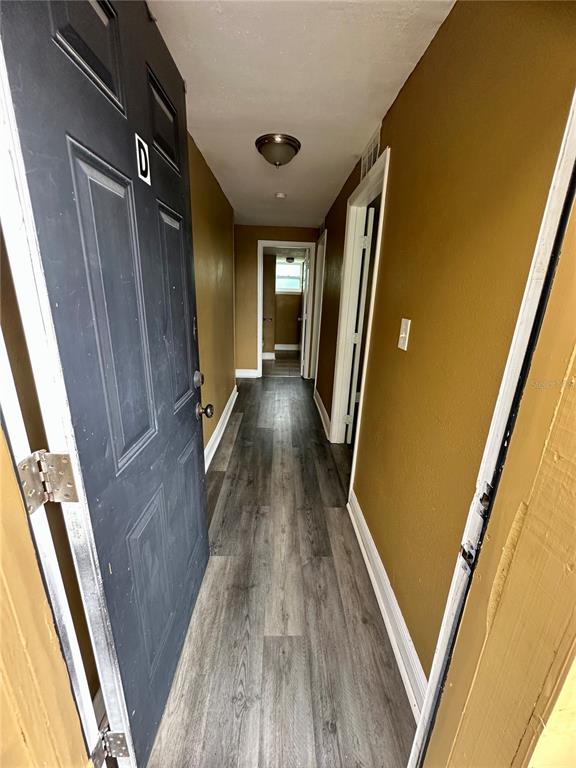 A hallway with gray wood-look flooring leads to a doorway at the end — 2907 N 15TH STREET UNIT D, TAMPA, FL