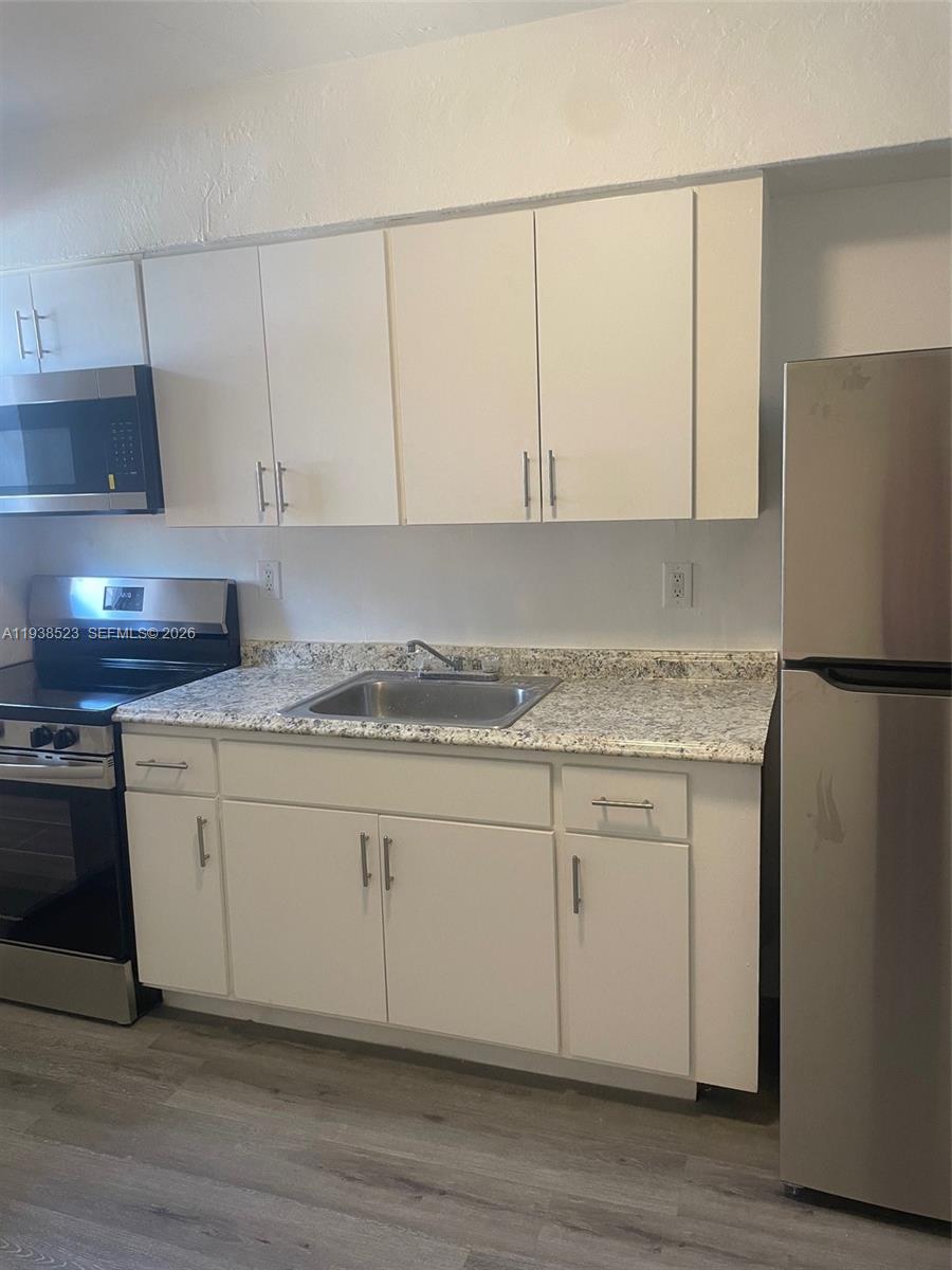 A kitchen features white cabinets, stainless steel appliances, and a speckled granite countertop — 1831 NW 41 st, Miami FL 33142, MIAMI, FL