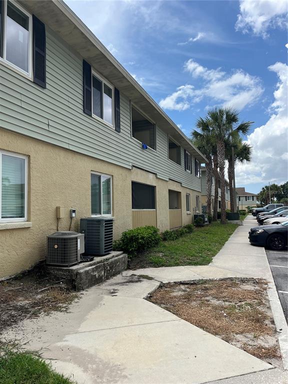 The exterior of a multi-story apartment building features light-colored siding, stucco walls, and air conditioning units — 528 GOLDEN RAINTREE PLACE, BRANDON, FL