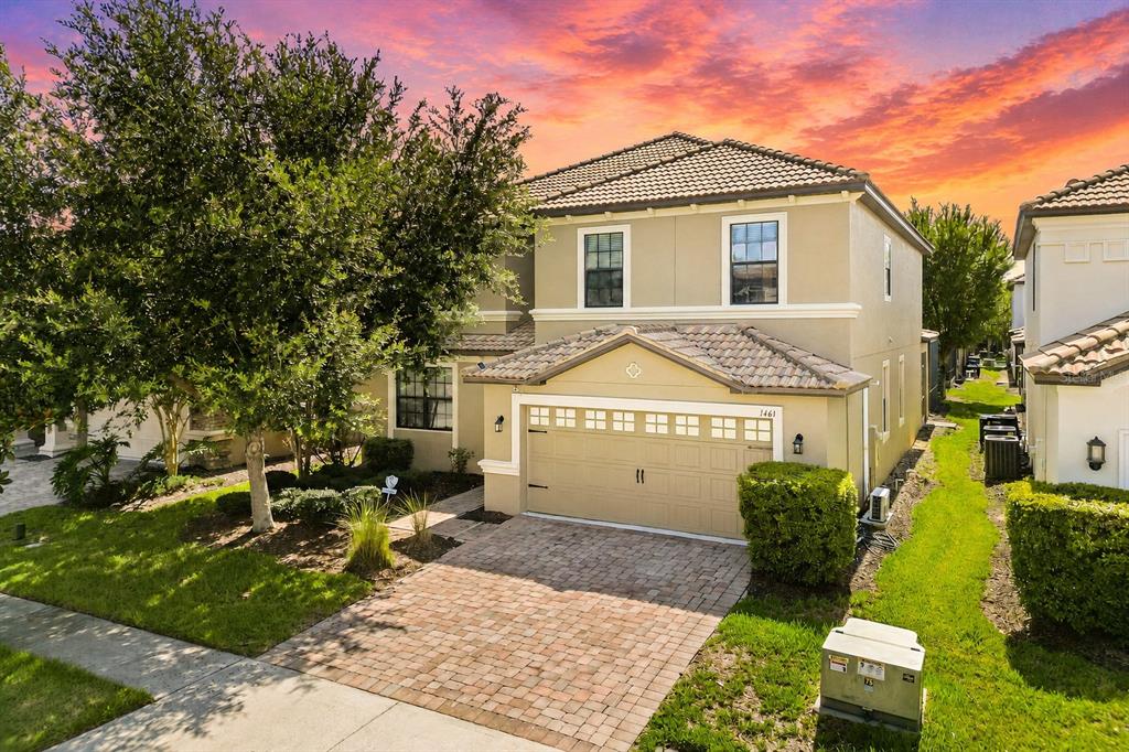 A two-story suburban house with a tan stucco exterior, tile roof, and brick paver driveway — 1461 MYRTLEWOOD STREET, DAVENPORT, FL