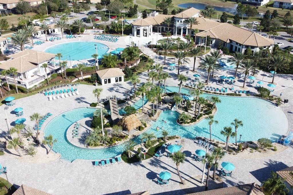 An aerial view shows a large community swimming pool complex with palm trees and buildings — 1461 MYRTLEWOOD STREET, DAVENPORT, FL