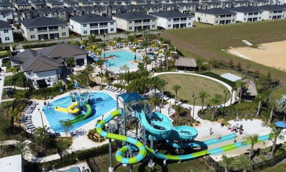 An aerial view shows a community swimming pool complex with water slides and surrounding houses — 1461 MYRTLEWOOD STREET, DAVENPORT, FL