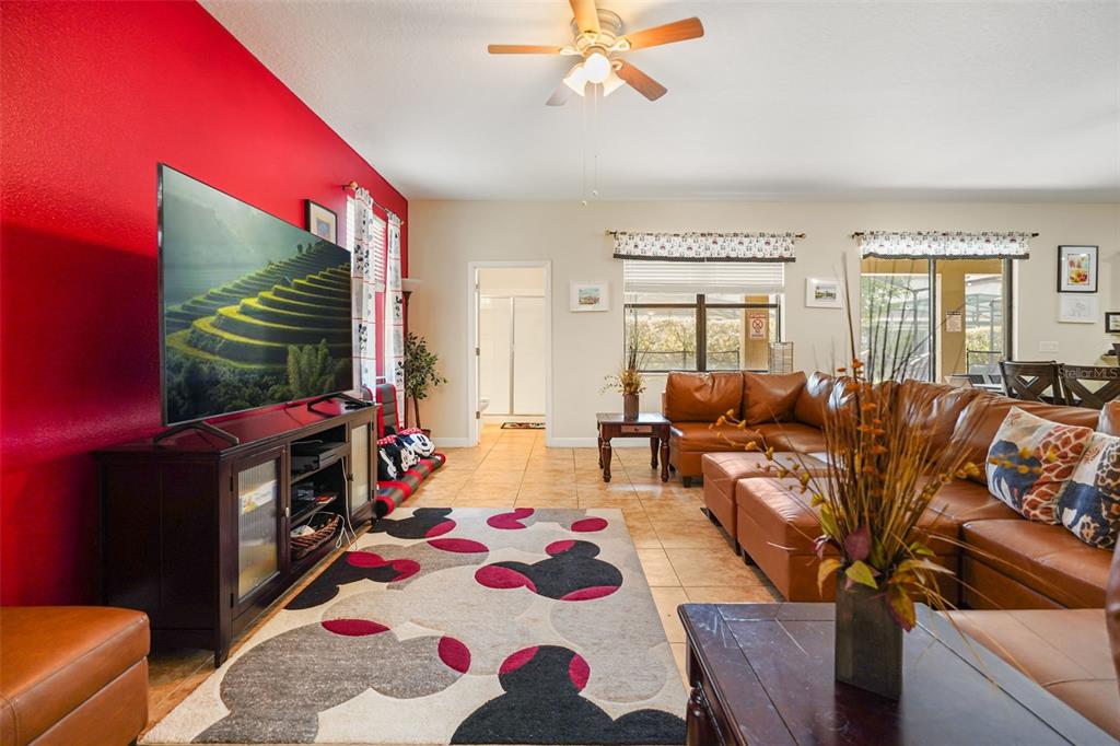 A living room features a red accent wall, a Mickey Mouse rug, and leather furniture — 1461 MYRTLEWOOD STREET, DAVENPORT, FL