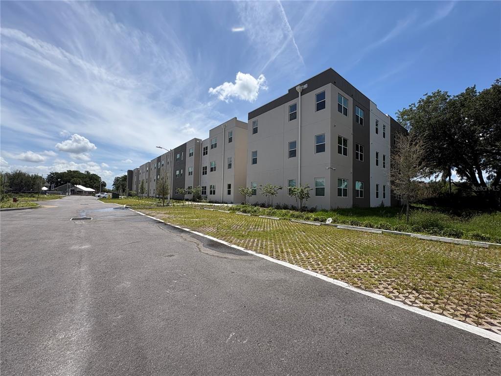 A multi-story apartment building with a paved parking lot and permeable paver spaces — 4424 S TEXAS AVENUE UNIT 1-112, ORLANDO, FL